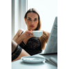 A beautiful woman drinks her coffee in the morning while reading the daily newspaper.